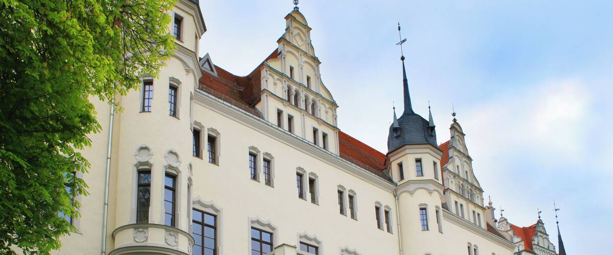 A large, ornate building with multiple towers and a red roof.