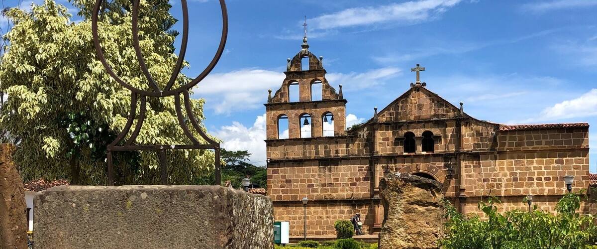 A historic church with a bell tower, surrounded by greenery and a stone pathway.