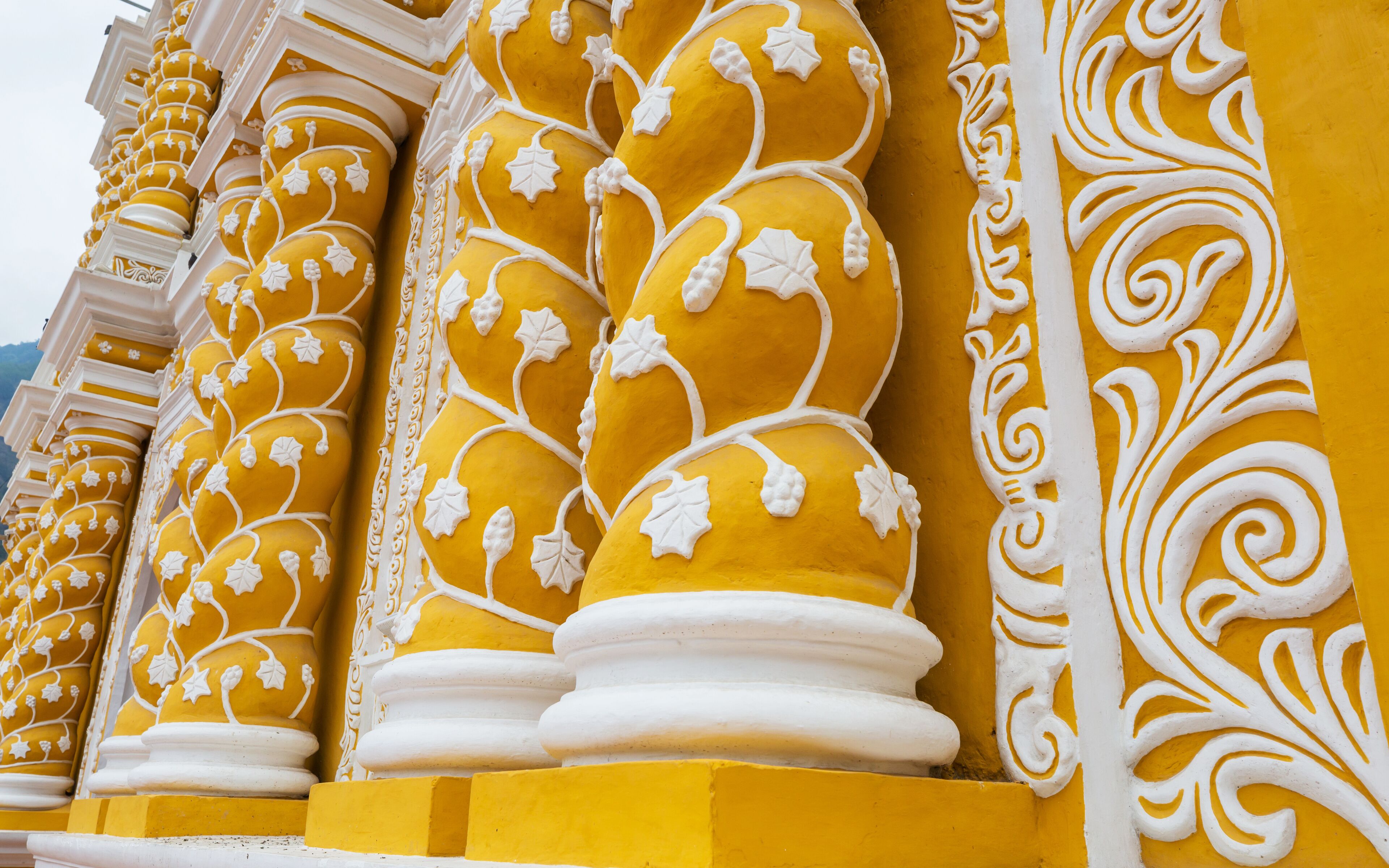 Ornate yellow columns with white floral carvings.