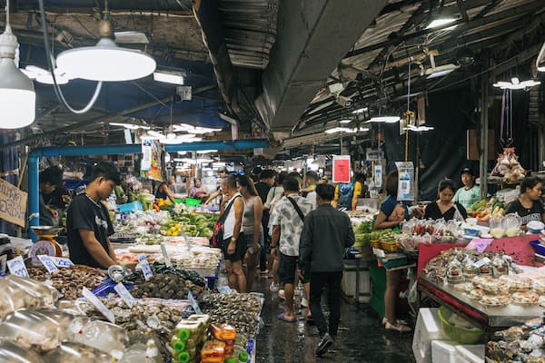 A bustling indoor market with various stalls selling seafood and vegetables.
