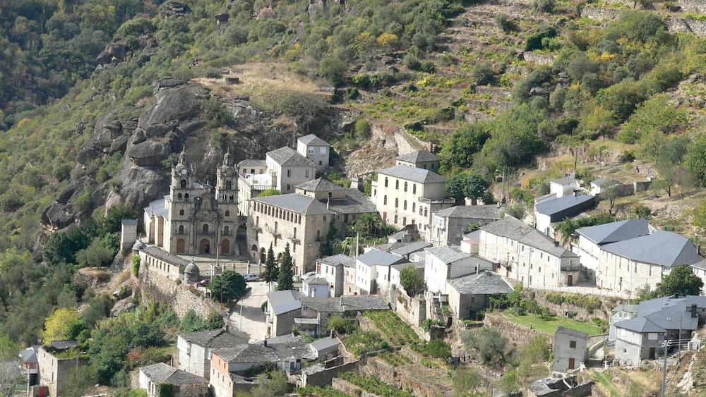 Ein historisches Dorf mit Steinhäusern, eingebettet in eine hügelige Landschaft.