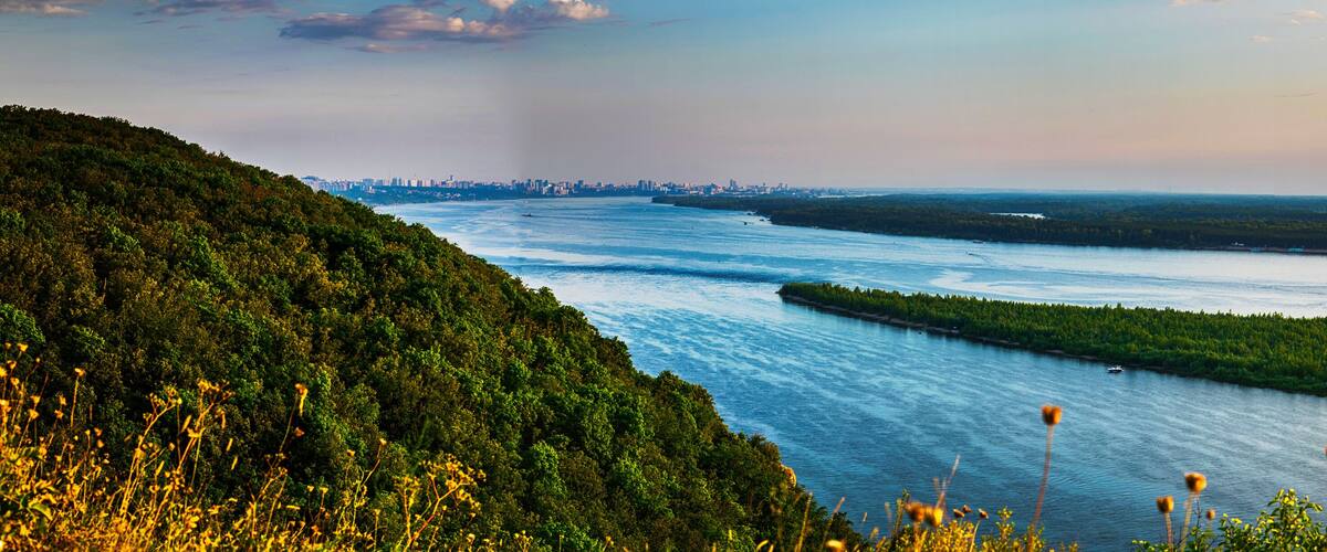 Panoramic view on Volga river and island with green forest during summer sunset from hill near Samara city