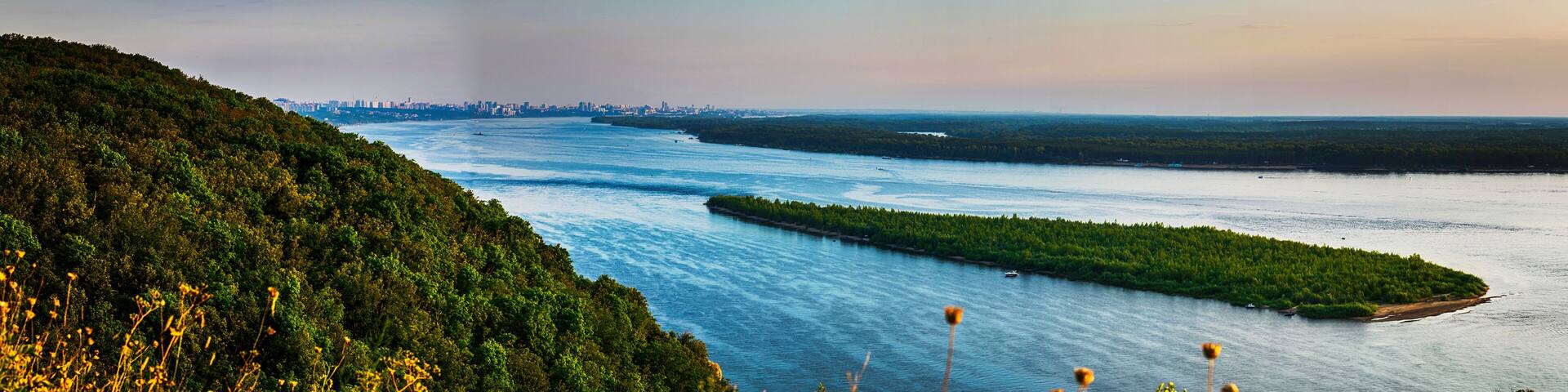 Panoramic view on Volga river and island with green forest during summer sunset from hill near Samara city
