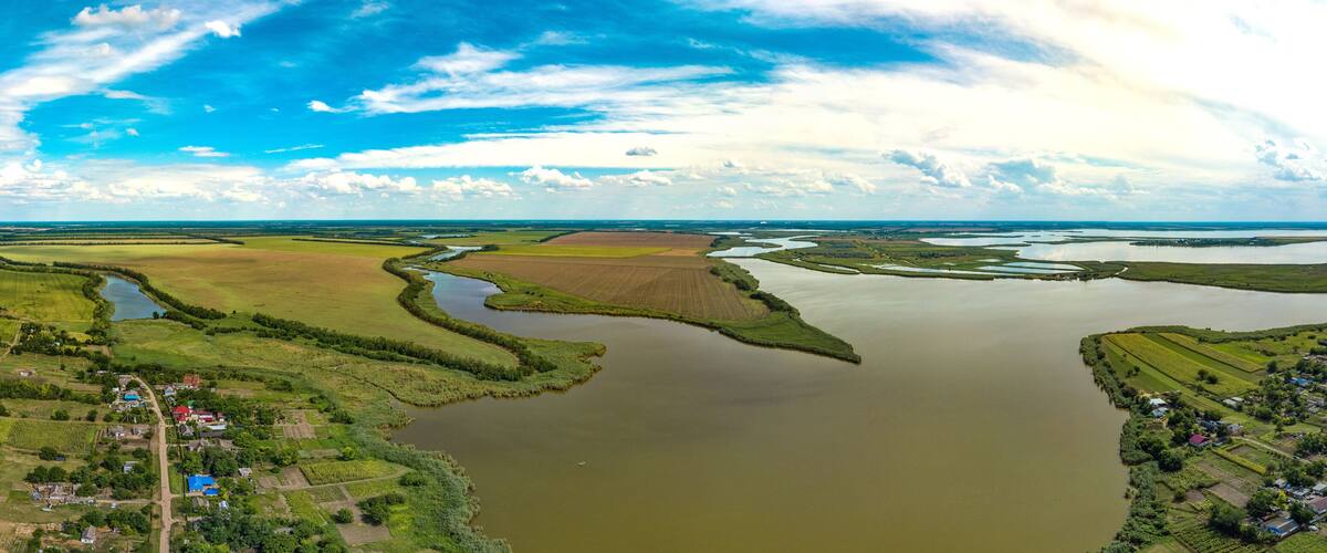 village houses of the village of Kinovia near the luman of the Beysug river (South of Russia, Krasnodar Territory) - large aerial panorama with a sunny hot summer day