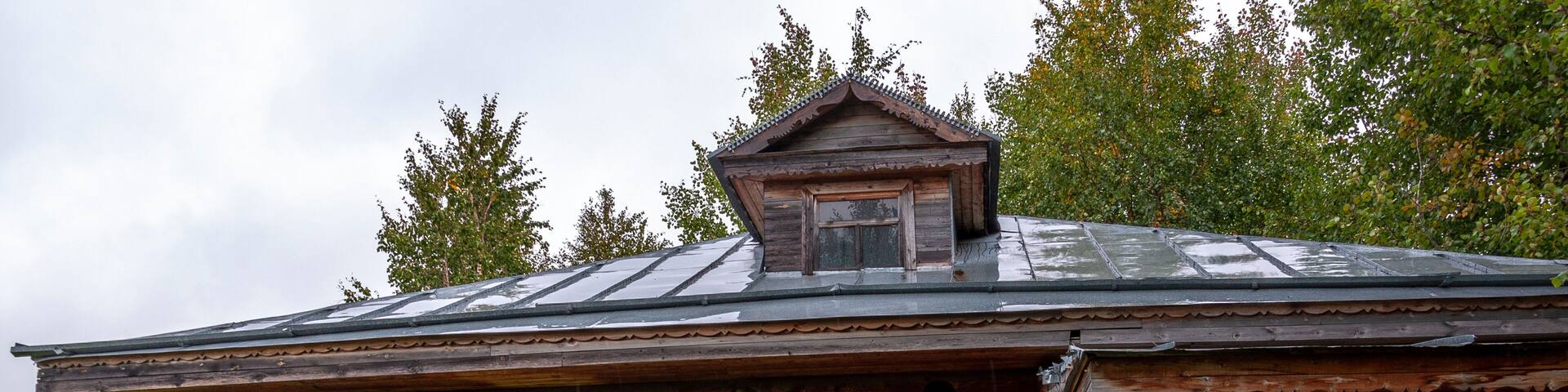 Reiny clouds in the cold autumn sky over village with small wood log local houses and low fences in the park. Travelling on the suburb roads. People living
