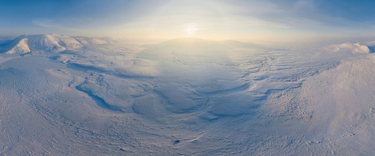 Aerial view of cold, snowy tundra landscape with beautiful mountain peaks, Vorkuta, Komi Republic, Russia.