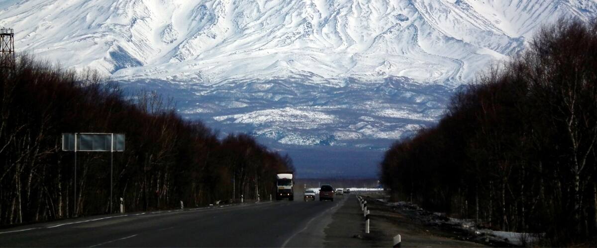 A snow-covered mountain with a road leading towards it.