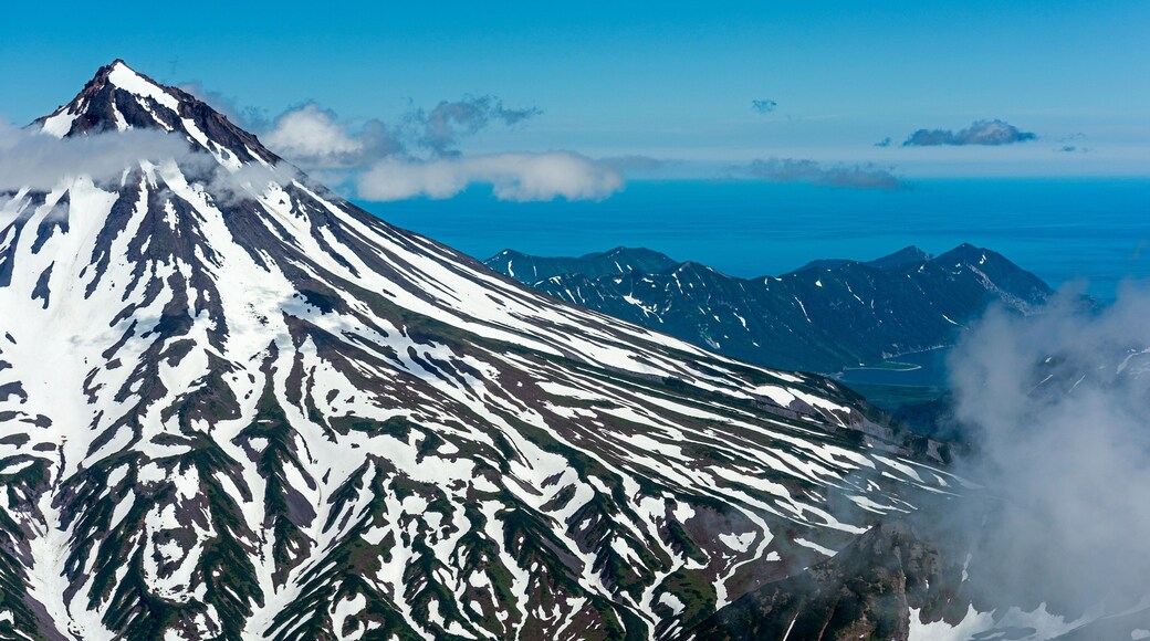 Aerial view of snowcapped Vilyuchinsk Volcano surrounded by clouds and a breathtaking landscape, Kamchatka Peninsula, Russia.