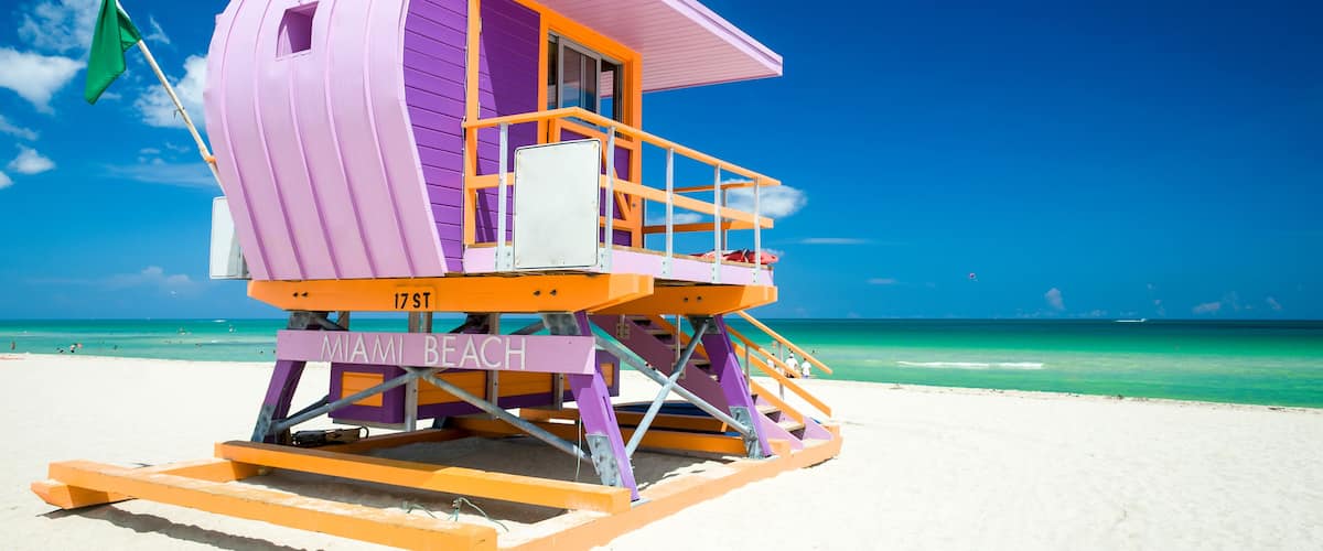 Vibrant sunny view of lifeguard tower painted pastel colors under bright blue sky on South Beach, Miami, Florida