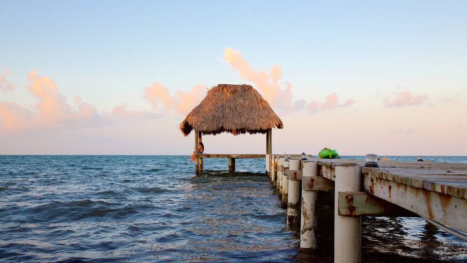 A thatched-roof hut on a wooden pier extending into the ocean.
