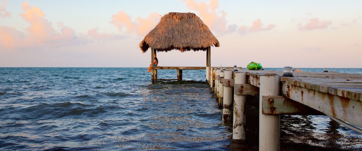 A thatched-roof hut on a wooden pier extending into the ocean.