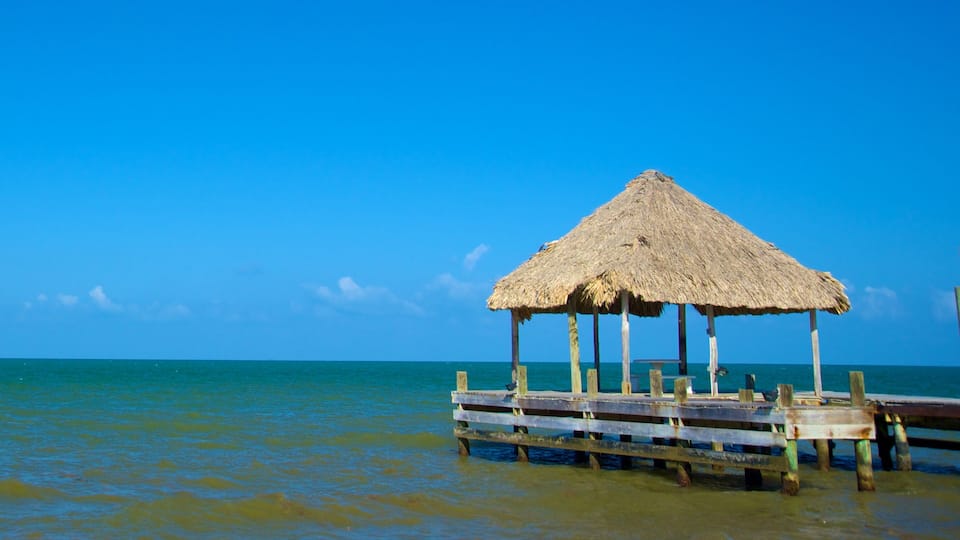 A thatched-roof hut on a wooden pier extending into turquoise waters.
