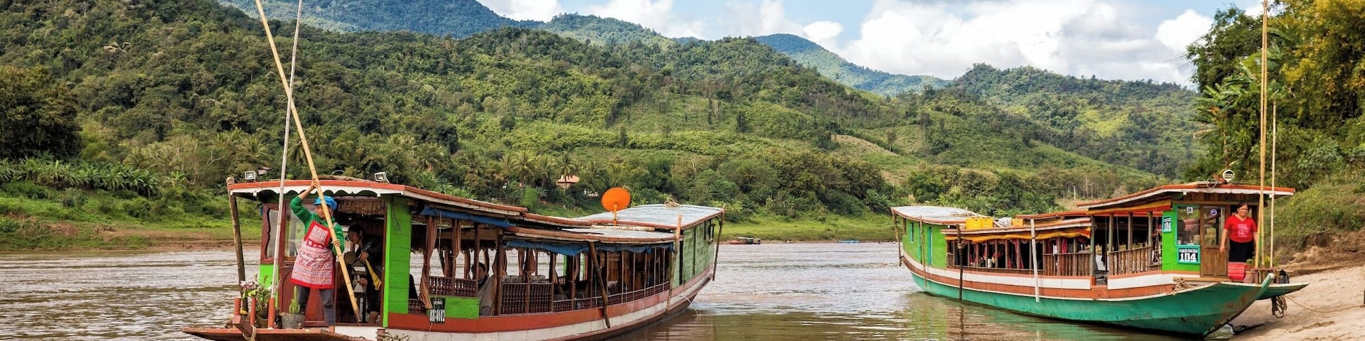 Two boats on a river with mountains in the background.