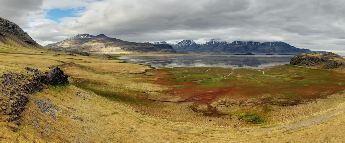 A mountainous landscape with a lake and a road.