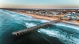 Ocean beach and fishing pier aerial drone shot