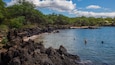 A coastal area with rocky shores, clear blue water, and lush greenery.
