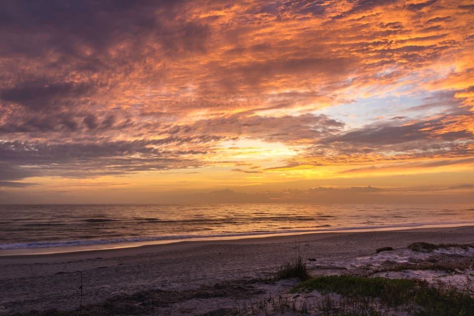 Una playa al atardecer con un cielo colorido y olas del océano.