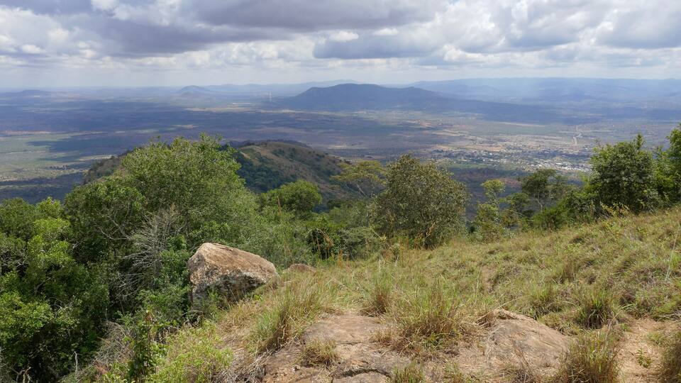 A mountainous landscape with dense vegetation and a distant view of a valley.