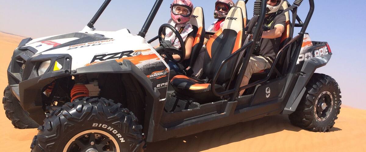 A Polaris RZR 4x4 off-road vehicle on a sandy terrain.