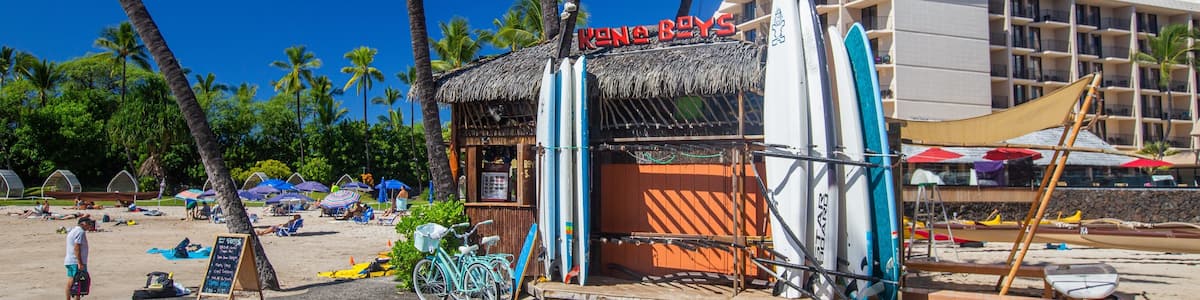 Ein Restaurant direkt am Strand namens 'Kona Boys' mit Surfbrettern und Fahrrädern.