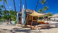 A beachside surf shop with surfboards and a sign listing services like canoe rides and snorkel gear.