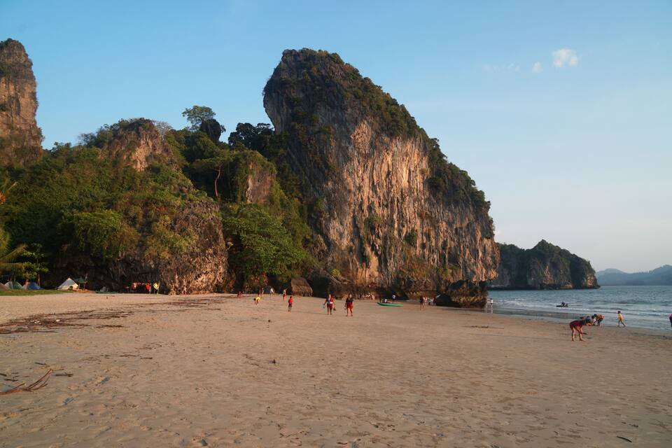 A beach with people, tents, and a large cliff.