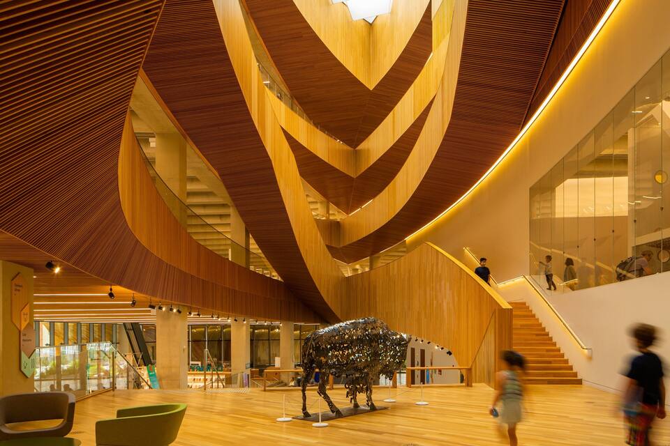 A modern interior with wooden slats on the ceiling and a sculpture of a cow.