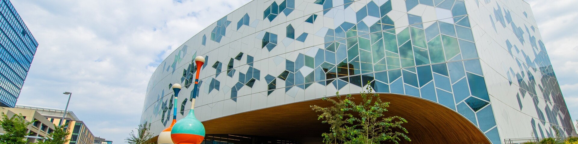 Un edificio moderno con fachada geométrica y entrada curva.