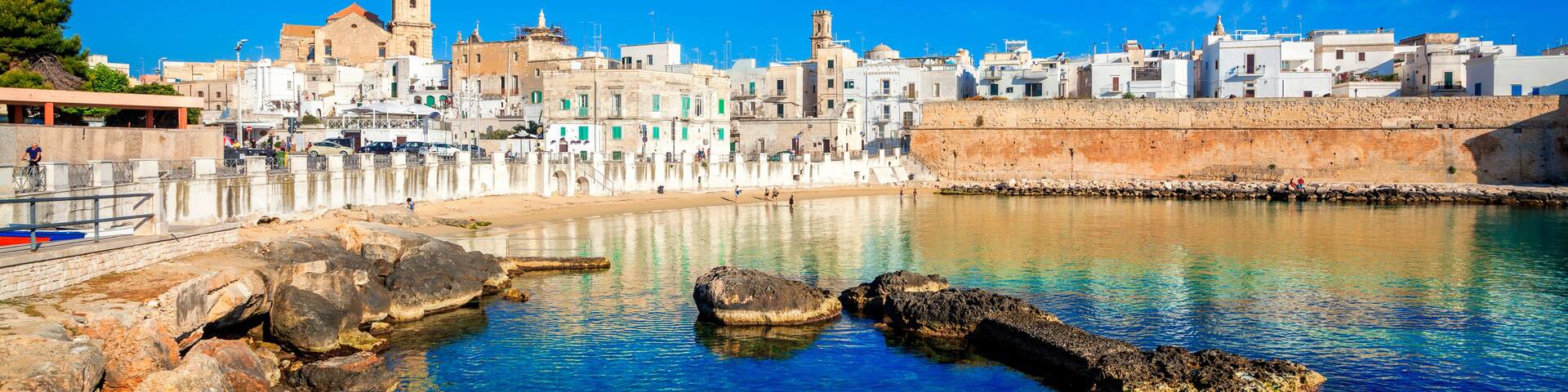 A coastal town with a prominent tower, clear blue waters, and rocky shoreline.