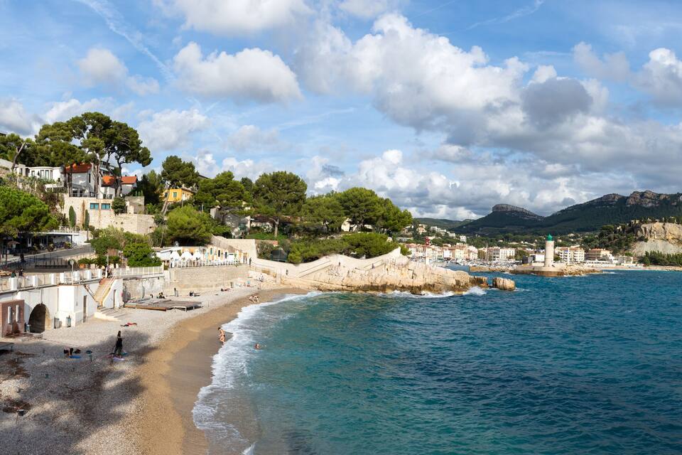 Uma vila costeira com praia, falésias rochosas e uma torre.