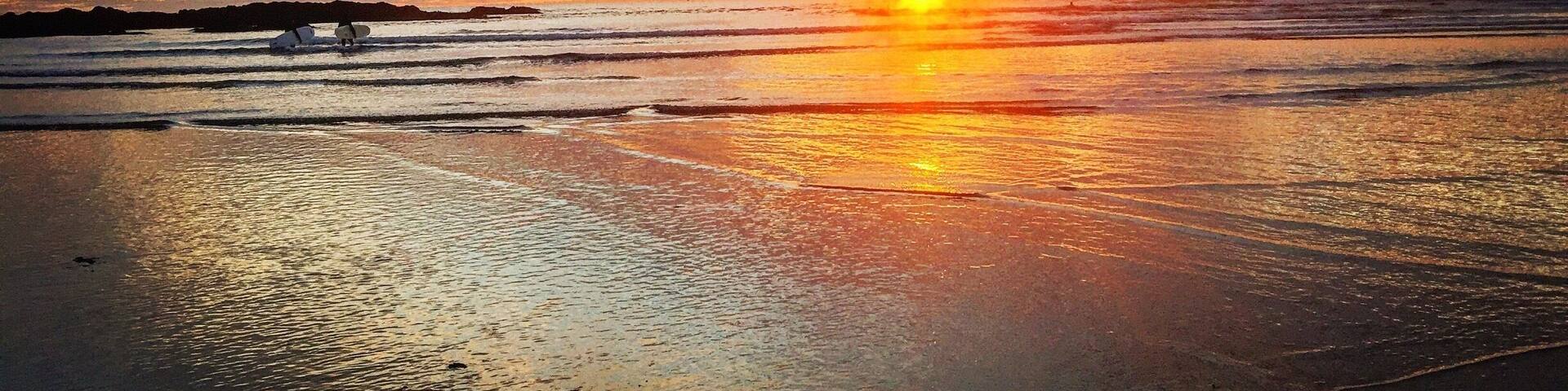 A beach at sunset with waves and a clear sky.