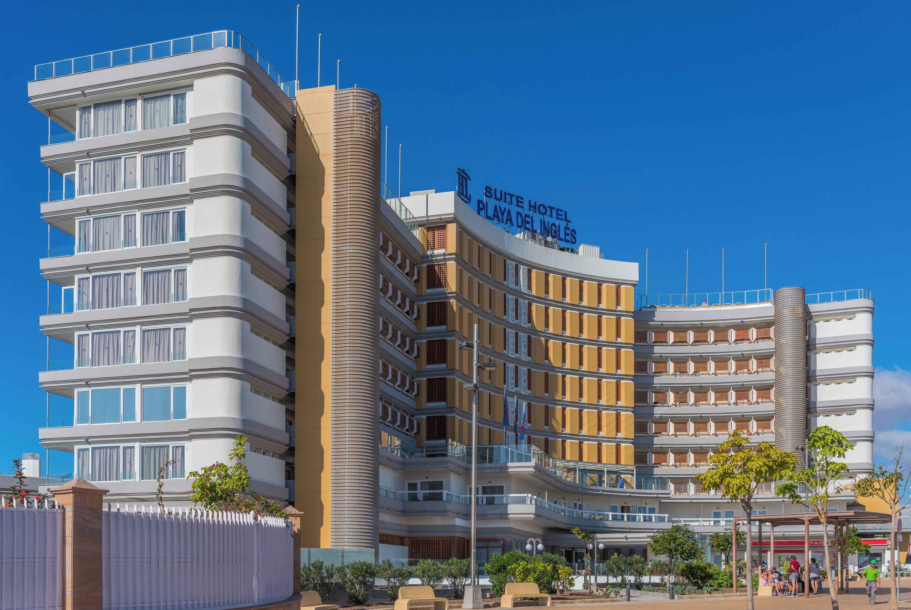 A modern hotel with multiple balconies and a clear blue sky.