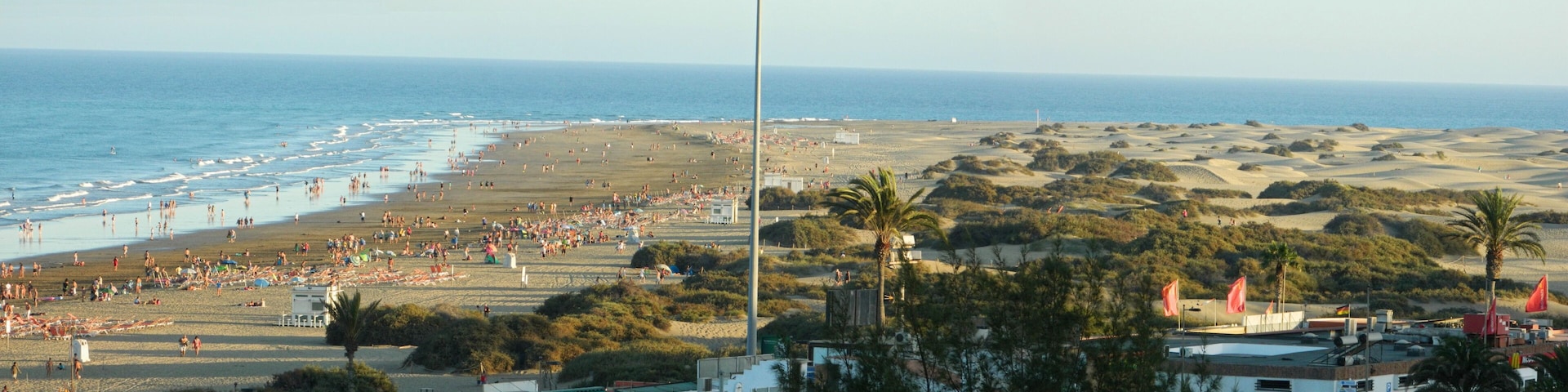 Una playa con gente, una torre de salvavidas y un paisaje de dunas.
