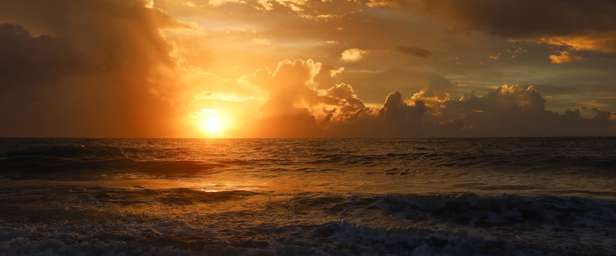A sunset over the ocean with clouds reflecting the sun's light.