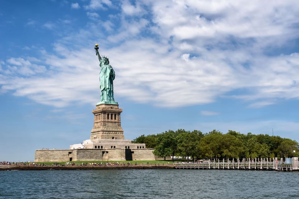 La Statua della Libertà sull'Isola della Libertà, con cielo sereno e acque calme.