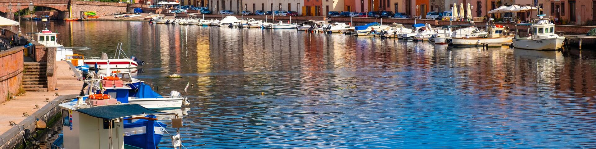 Bosa, Sardinia, Italy - Panoramic view of the old town quarter of Bosa by the Temo river embankment with colorful tenement houses and boats