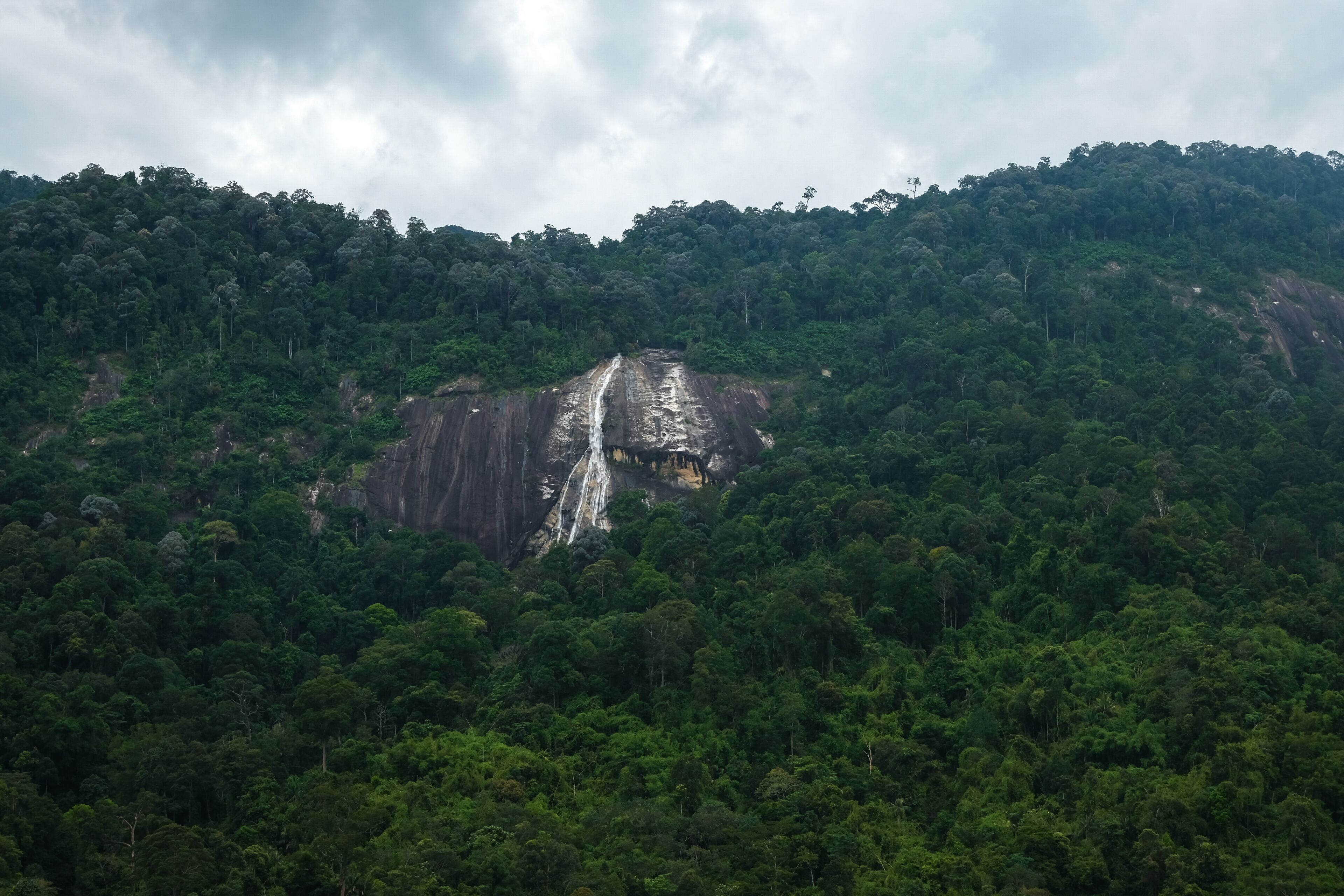 Background image of tropical mountain and Jelawang Waterfall in Gunung Stong National Park, Dabong, Kelantan, Malaysia.
