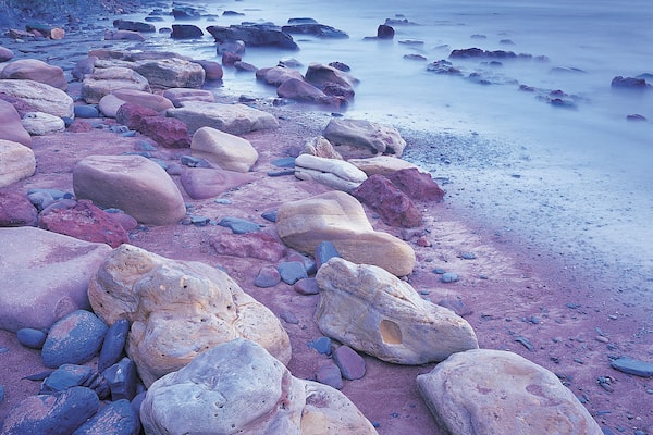 Ein felsiger Strand mit großen Felsen und ruhigem Meer.