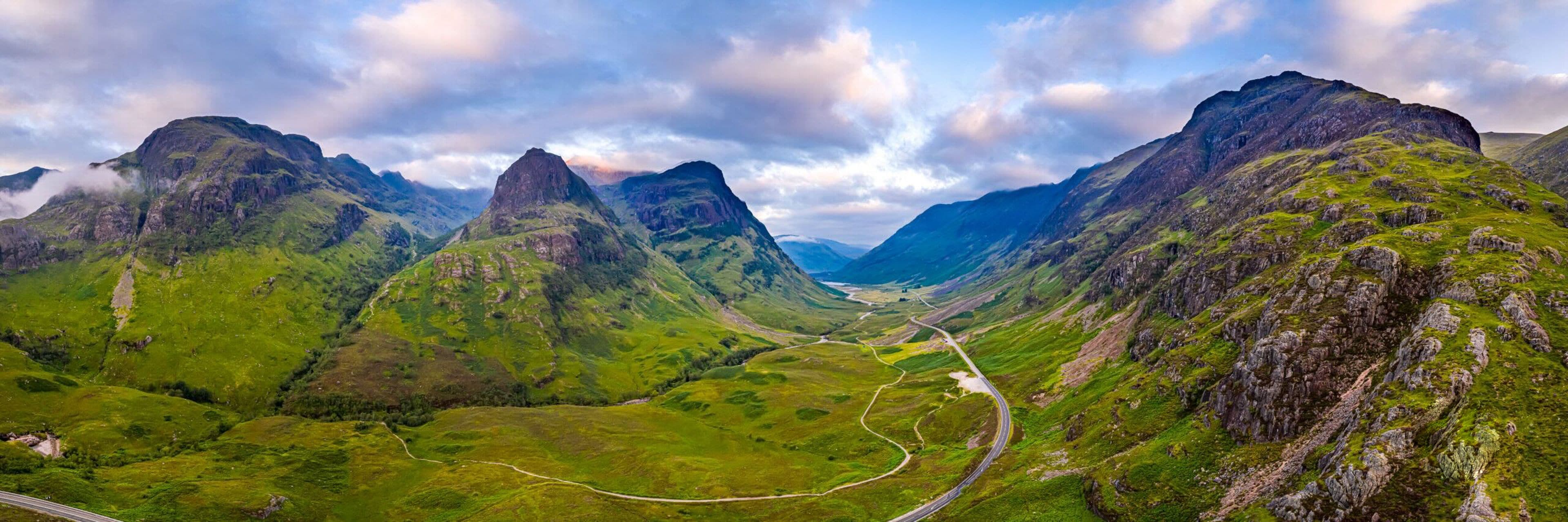 A mountainous landscape with a winding road through a valley.