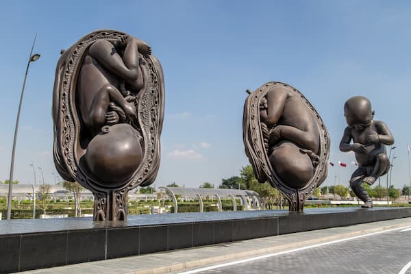 Eine Skulptur eines Fötus in einem Ei, nebenan eine kleinere Version davon.