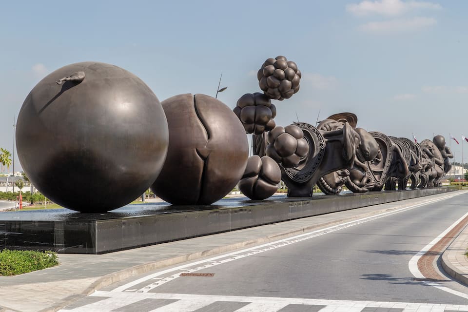 Una gran escultura de figuras abstractas sobre un puente.