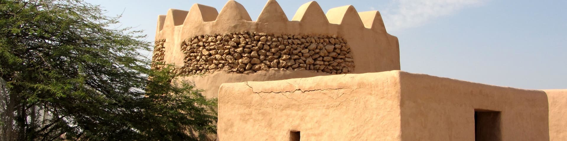 Un bâtiment traditionnel construit en briques de terre crue, surmonté d’une partie supérieure crénelée et doté d’une petite porte.