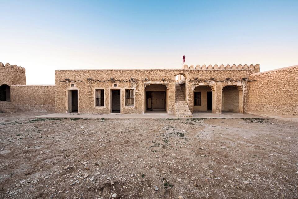A historic stone building with arched doorways and a flag on top.