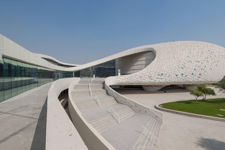 Een modern architectonisch gebouw met een uniek, gebogen ontwerp en een geometrisch patroon op de gevel.