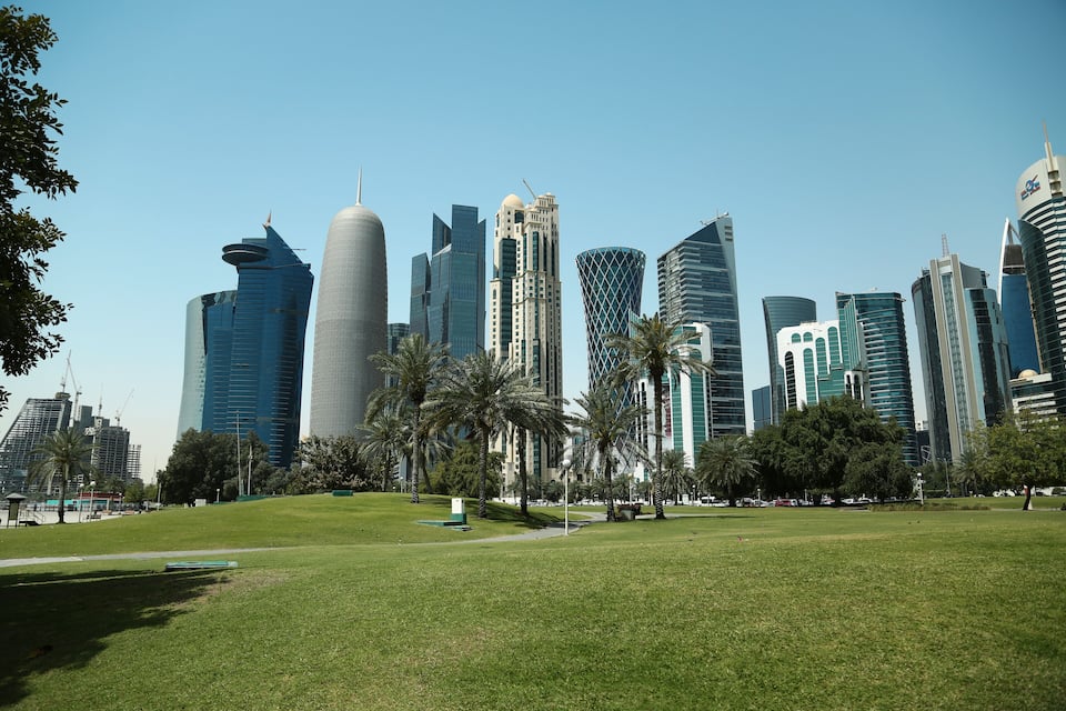 A cityscape with modern skyscrapers and a central grassy park area.