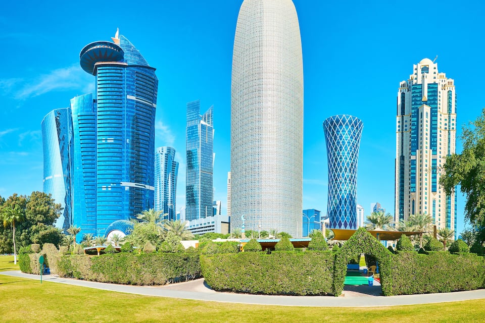 A cityscape with modern skyscrapers, a prominent curved building, and well-maintained greenery.