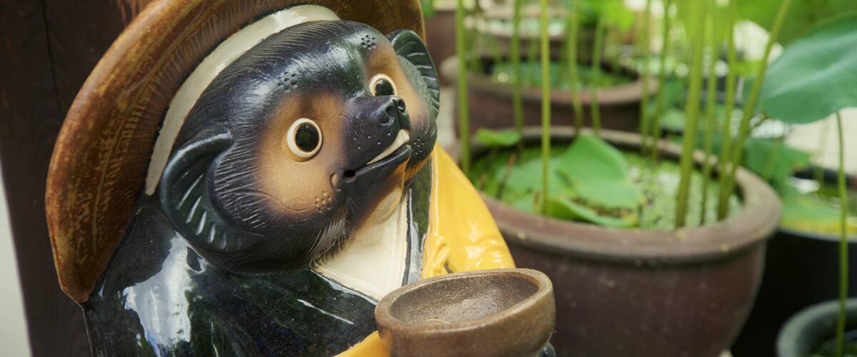 A ceramic figurine of a bear wearing a hat and holding a bowl.