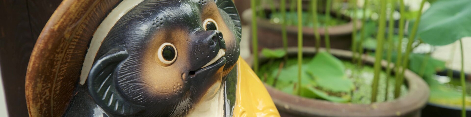 A ceramic figurine of a bear wearing a hat and holding a bowl.