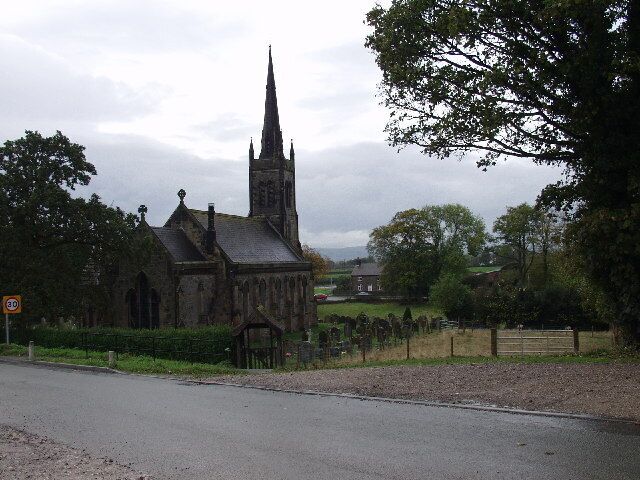 A church with a tall spire, surrounded by trees and a fence.