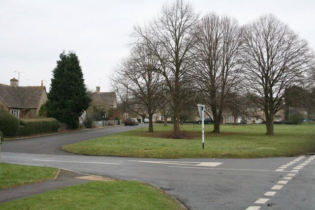 A residential street with houses, a roundabout, and leafless trees.